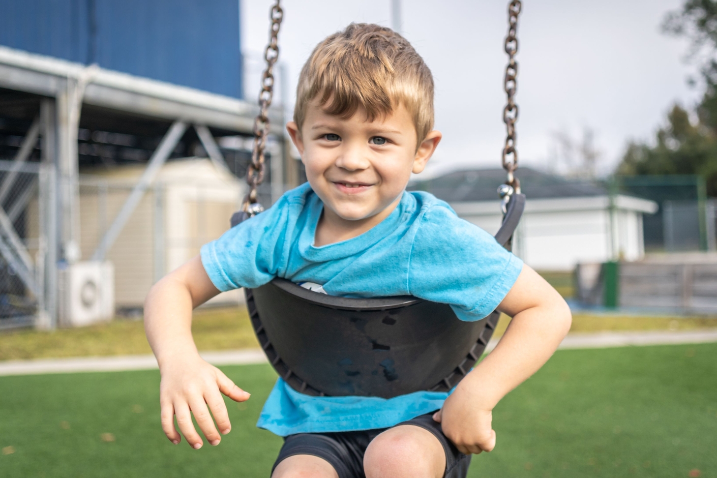 Preschool boy smiling on swing.